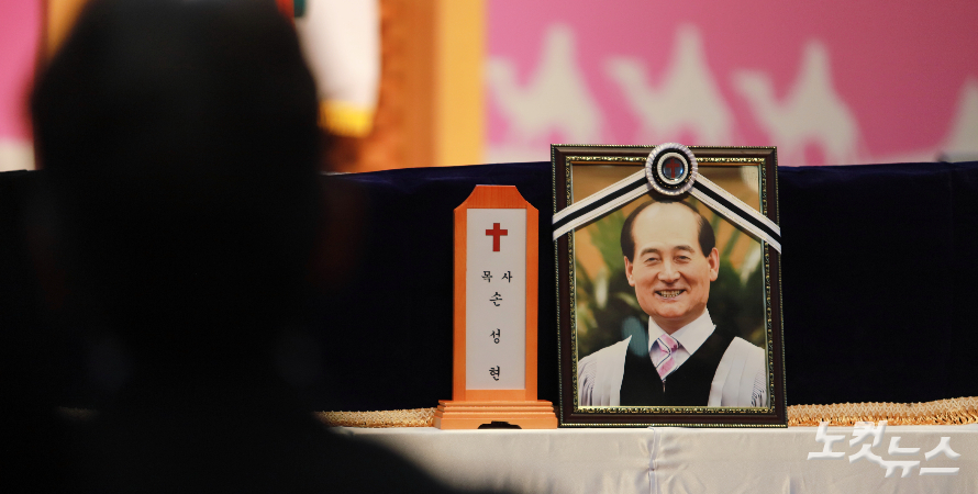 환하게 웃고 있는 故 손성현 원로목사 사진과 아들 손희선 목사의 뒷 모습. 한세민 기자