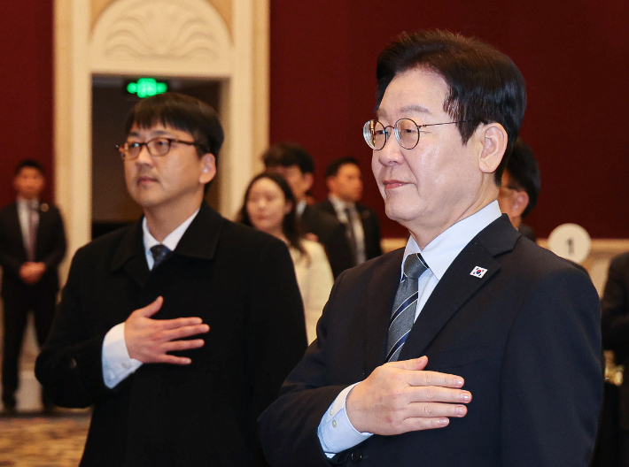 중국을 국빈방문 중인 이재명 대통령이 7일 상하이의 한 호텔에서 열린 순방 기자단 오찬 간담회에서 국기에 경례하고 있다. 연합뉴스