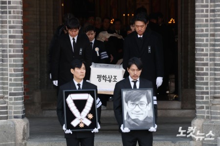 9일 오전 서울 중구 명동성당에서 열린 故 안성기의 장례 미사가 끝난 뒤 영결식을 위해 고인의 영정과 금관문화훈장을 든 배우 정우성, 이정재가 영결식장으로 향하고 있다.