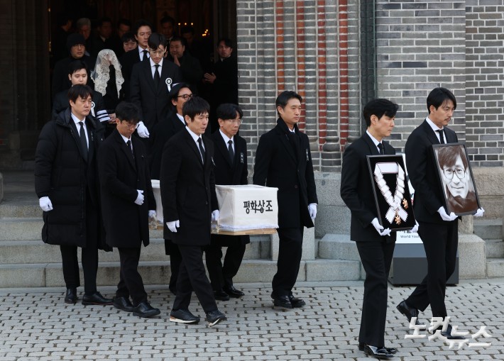 9일 오전 서울 중구 명동성당에서 열린 故 안성기의 장례 미사가 끝난 뒤 영결식을 위해 고인의 영정과 금관문화훈장을 든 배우 정우성, 이정재가 영결식장으로 향하고 있다.