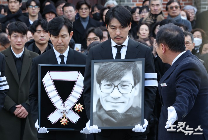 9일 오전 서울 중구 명동성당에서 열린 故 안성기의 장례 미사가 끝난 뒤 영결식을 위해 고인의 영정과 금관문화훈장을 든 배우 정우성, 이정재가 영결식장으로 향하고 있다.