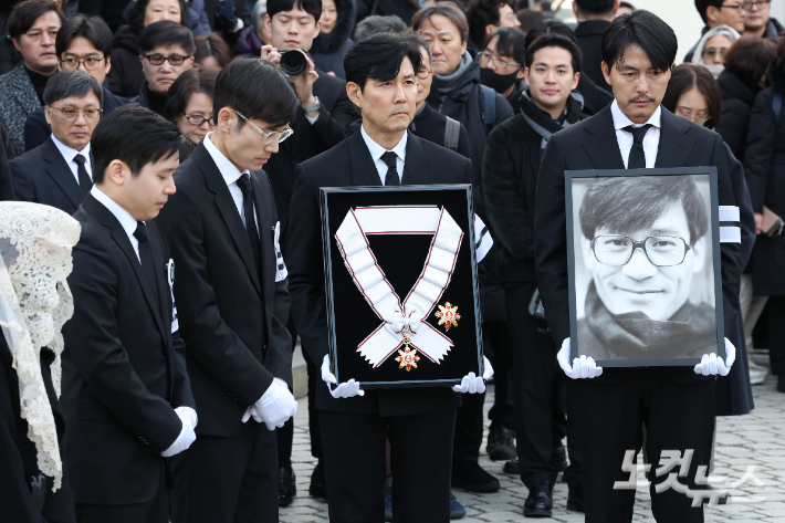 9일 오전 서울 중구 명동성당에서 열린 故 안성기의 장례 미사가 끝난 뒤 영결식을 위해 고인의 영정과 금관문화훈장을 든 배우 정우성, 이정재가 영결식장으로 향하고 있다. 류영주 기자