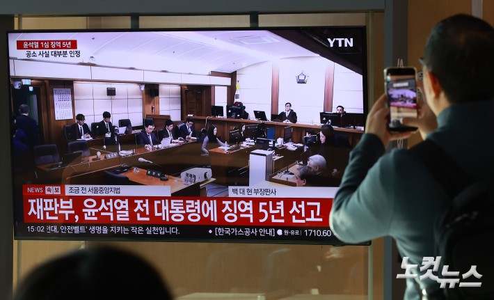 16일 오후 서울역 대합실에서 시민들이 고위공직자범죄수사처(공수처) 체포 방해 혐의 등으로 기소된 윤석열 전 대통령에 대한 1심 선고 공판 생중계를 지켜보고 있다.