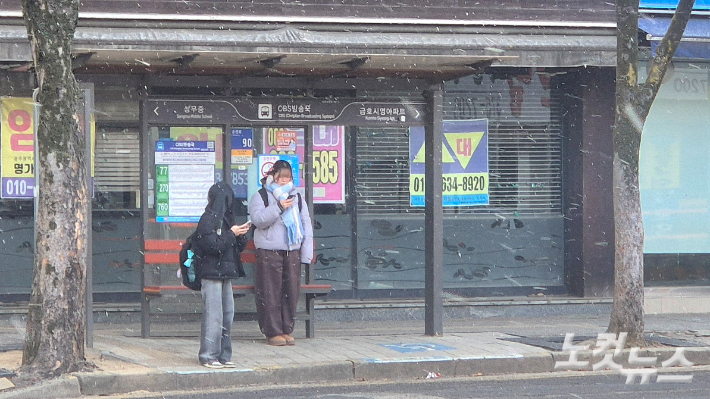 눈이 내리는 21일 오전 9시쯤 광주 서구의 한 정류장에서 학생들이 버스를 기다리고 있다. 한아름 기자