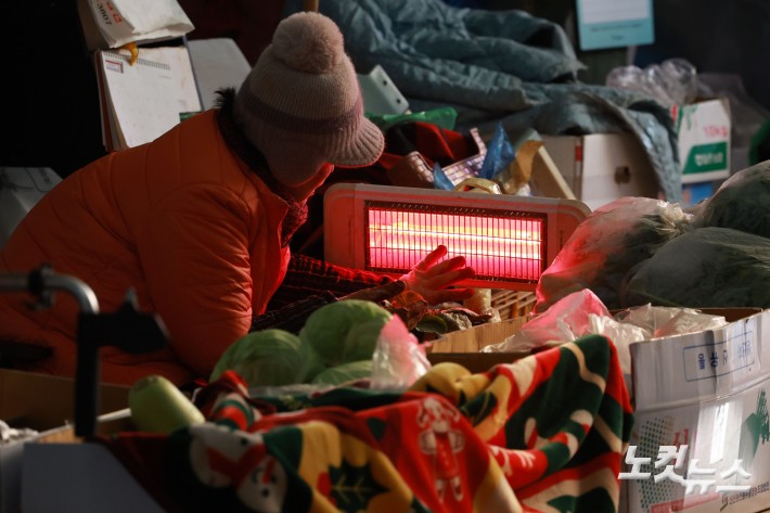 연일 한파가 이어지고 있는 가운데 29일 서울 서대문구 인왕시장에 상인들이 난로에 손을 녹이고 있다.