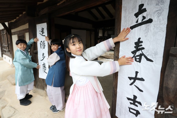 절기상 입춘(立春)인 4일 오전 서울 종로구 국립민속박물관 내 오촌댁 대문에 어린이들이 입춘첩을 붙이고 있다.