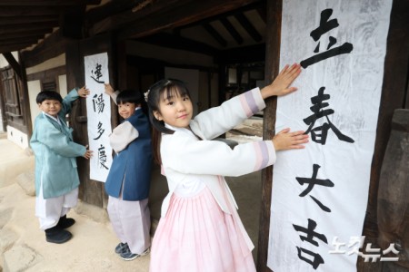 절기상 입춘(立春)인 4일 오전 서울 종로구 국립민속박물관 내 오촌댁 대문에 어린이들이 입춘첩을 붙이고 있다.