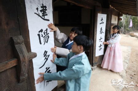 절기상 입춘(立春)인 4일 오전 서울 종로구 국립민속박물관 내 오촌댁 대문에 어린이들이 입춘첩을 붙이고 있다.