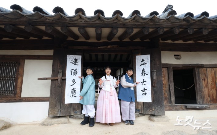 절기상 입춘(立春)인 4일 오전 서울 종로구 국립민속박물관 내 오촌댁 대문에 어린이들이 입춘첩을 붙이고 있다.