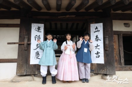 절기상 입춘(立春)인 4일 오전 서울 종로구 국립민속박물관 내 오촌댁 대문에 어린이들이 입춘첩을 붙이고 있다.