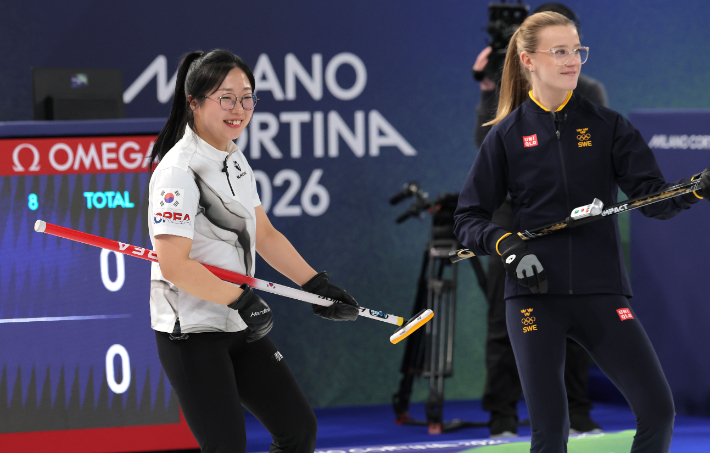컬링 믹스더블 국가대표 김선영이 4일(현지 시각) 정전으로 라운드로빈 경기가 중단된 이탈리아 코르티나담페초 컬링 올림픽 스타디움에서 경기장 조명이 전력 복구 중 깜빡이자 상대 스웨덴 선수인 이사벨라 브라노와 함께 브룸을 들고 기타를 치는 동작을 하고 있다. 연합뉴스 
