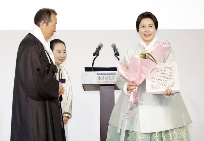 김혜경 여사가 6일 서울 중구 정동1928 아트센터에서 열린 2026 설맞이 한복인 신년회에서 정순훈 한복세계화재단 이사장, 구혜자 침선장(한복세계화재단 고문)으로부터 한복 명예홍보대사 추대패를 전달받은 뒤 기념촬영을 하고 있다. 연합뉴스