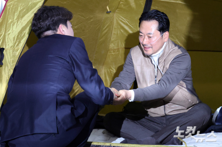 이준석 개혁신당 대표가 지난달 21일 서울 여의도 국회 로텐더홀에서 단식투쟁 7일차를 맞은 장동혁 국민의힘 대표를 찾아 대화를 하고 손을 잡고 있다. 윤창원 기자