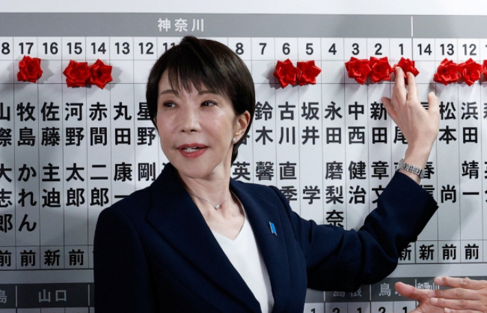 다카이치 사나에 일본 총리가 8일 중의원 선거(총선)에서 승리한 집권 자민당 후보 이름 위에 꽃을 붙이고 있다. 연합뉴스