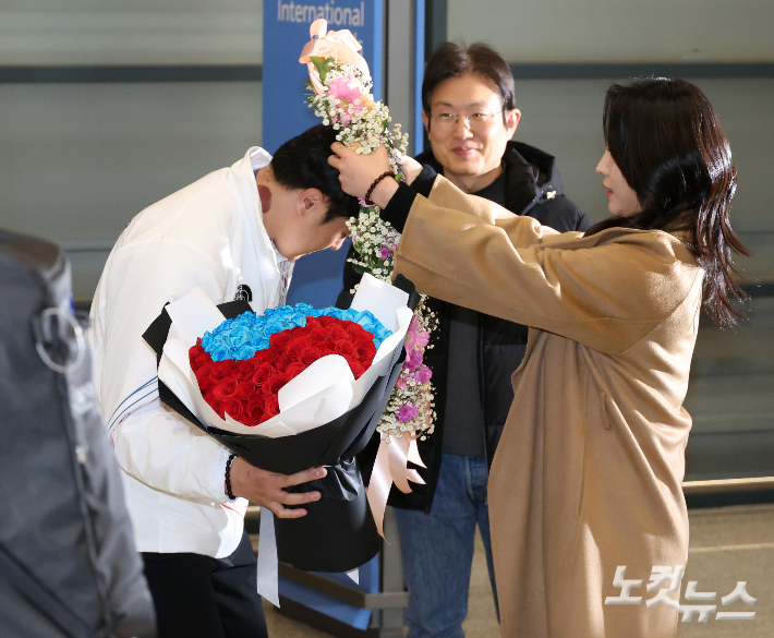 '2026 밀라노·코르티나담페초 동계올림픽' 스노보드 남자 평행 대회전에서 은메달을 획득한 김상겸이 10일 인천공항 1터미널을 통해 귀국, 부인으로부터 꽃목걸이를 받고 있다. 인천공항=황진환 기자