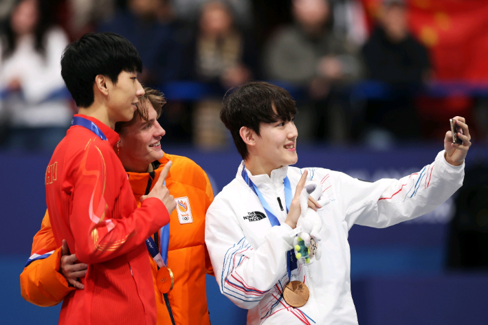 13일(한국시간) 이탈리아 밀라노 아이스스케이팅 아레나에서 열린 쇼트트랙 남자 1,000m 시상식에서 금메달 옌스 판트 바우트(네덜란드), 은메달 쑨룽(중국), 동메달 임종언(대한민국) 선수가 갤럭시 Z 플립7 올림픽 에디션으로 빅토리 셀피를 찍고 있다. 연합뉴스