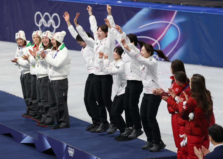 18일(현지시간) 이탈리아 밀라노 아이스스케이팅 아레나에서 열린 2026 밀라노·코르티나담페초 동계올림픽 쇼트트랙 여자 3000m 계주에서 금메달을 따낸 한국대표팀 선수들이 시상대에 오르며 손을 번쩍 들며 기쁨을 표현하고 있다. 연합뉴스
