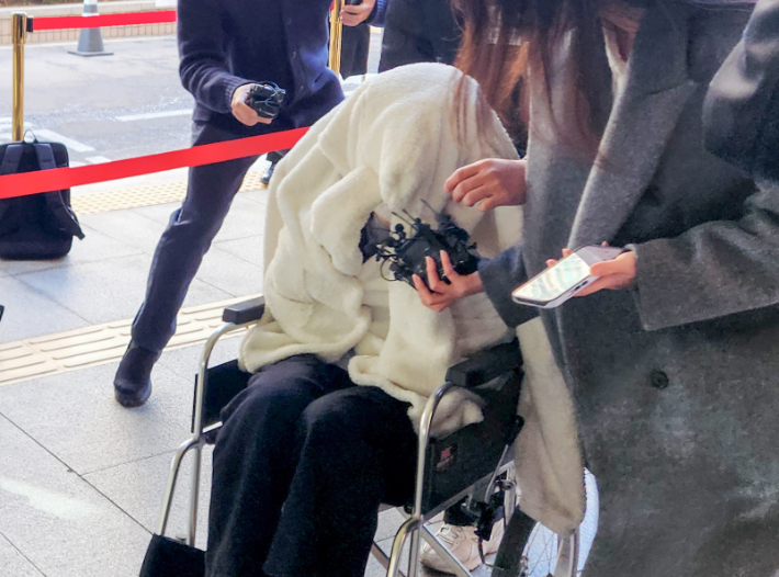 약에 취한 상태로 외제 SUV 차량을 몰고 반포대교를 달리다 한강 둔치로 추락한 운전자 A씨가 27일 서울 마포구 서부지방법원에서 열린 구속 전 피의자 심문(영장실질심사)에 옷으로 얼굴을 가리고 휠체어를 탄 채 출석하고 있다. 연합뉴스