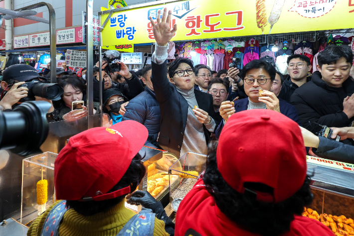 한동훈 국민의힘 전 대표가 27일 오후 대구 서문시장에 도착해 상인들이 건네는 음식을 먹고 있다. 연합뉴스