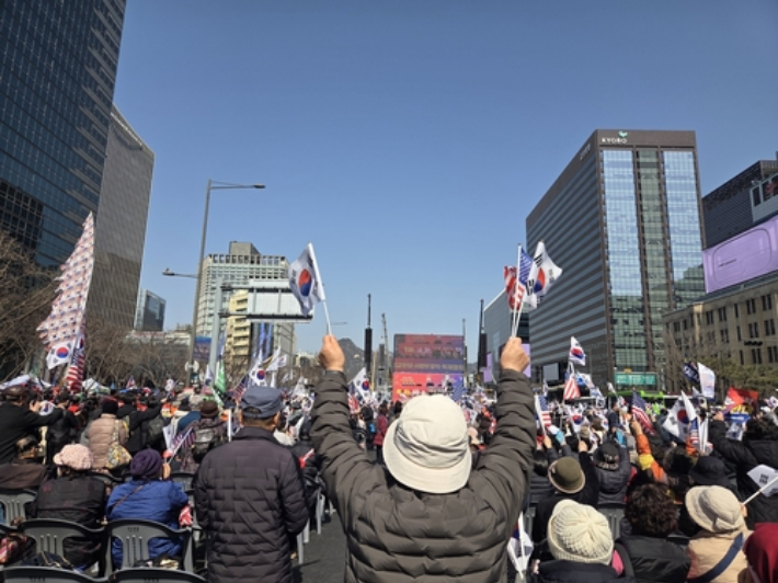 28일 서울 종로구 광화문광장 인근 동화면세 앞에서 대한민국바로세우기국민운동본부 주최로 열린 집회에서 참가자들이 태극기와 성조기를 흔들고 있다. 연합뉴스