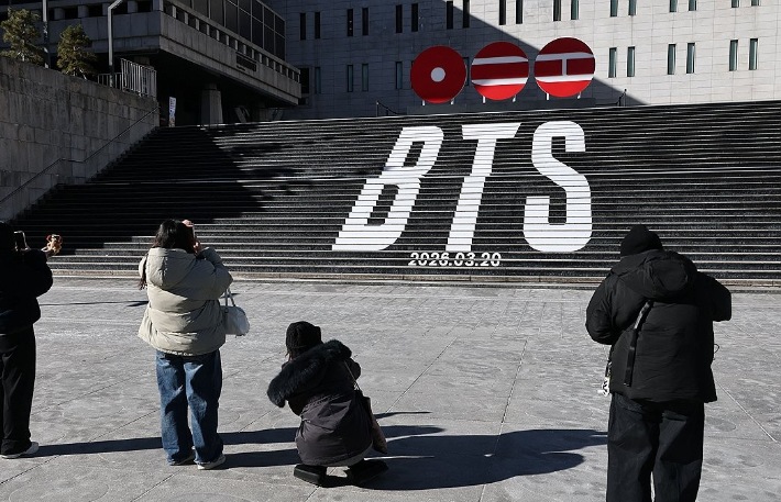 서울 종로구 세종문화회관 계단에서 외국인 관광객들이 그룹 방탄소년단(BTS)의 컴백을 알리는 홍보물을 기념촬영하고 있다. 연합뉴스