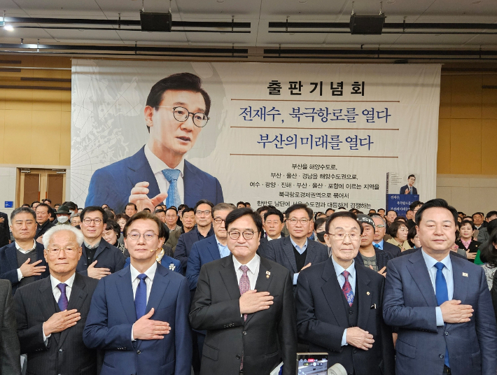 2일 부산 북항 국제전시컨벤션센터에서 열린 더불어민주당 전재수 의원의 출판기념회에서 참석자들이 국민의례를 하고 있다. 앞줄 왼쪽 두번째부터 전 의원, 우원식 국회의장, 문정수 전 부산시장, 김두관 전 의원.연합뉴스