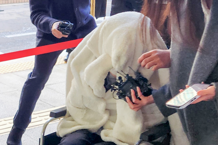 약에 취한 상태로 외제 SUV 차량을 몰고 반포대교를 달리다 한강 둔치로 추락한 운전자 A씨가 지난 2월 27일 서울 마포구 서부지방법원에서 열린 구속 전 피의자 심문(영장실질심사)에 옷으로 얼굴을 가리고 휠체어를 탄 채 출석하고 있다. 연합뉴스