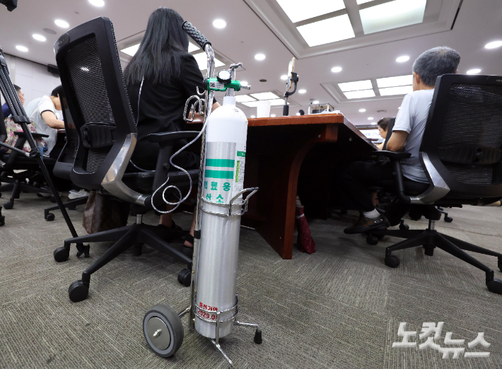 지난해 8월 국회 의원회관 1세미나실에서 열린 '가습기살균제 피해자단체 대표 간담회' 에 참석한 가습기살균제 중등도 피해자 민수연 씨가 산소호흡기 사용을 위한 의료용산소통을 옆에 두고 있다. 황진환 기자