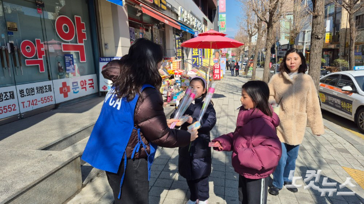 YWCA 이사진과 대학생 봉사자들이 시민들에게 장미꽃과 스펀지식빵을 나누고 있다. YWCA 제공