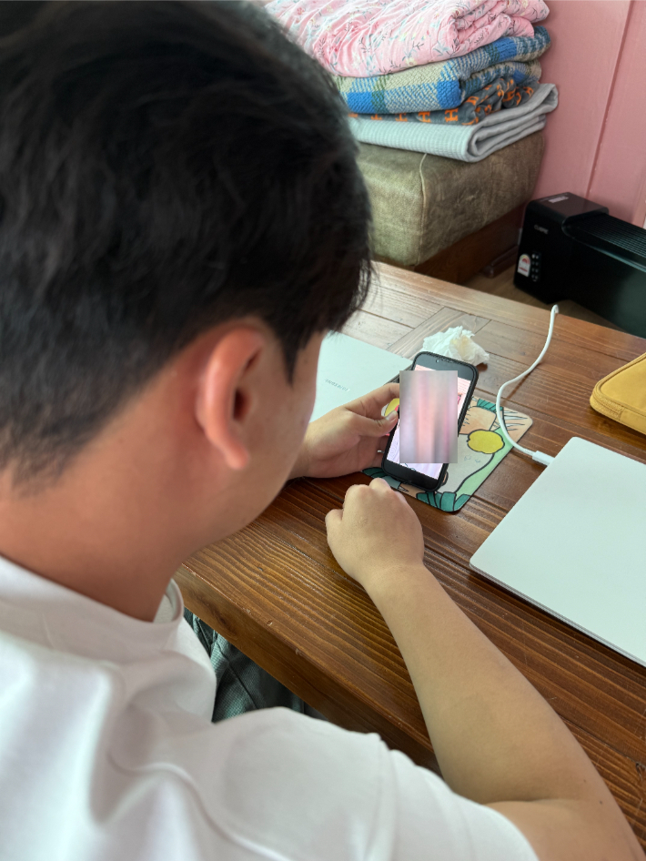 15세 때 어머니와 함께 탈북한 뒤 한국에서 대학생활 중인 김금성 씨가 현재 강제 북송 위기에 놓여 있는 어머니의 사진을 보고 있다. 독자 제공