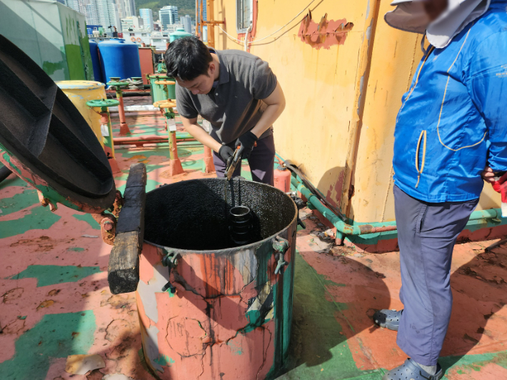 부산항 장기계류 중인 선박에 불법 보관하던 폐유에 대해 시료를 채취하고 있다. 남해지방해양경찰청 제공