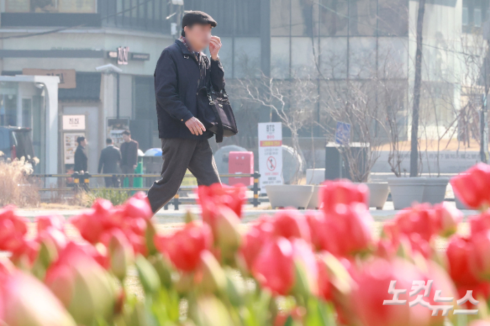 수도권과 충남 지역에 미세먼지 비상저감조치가 시행된 17일 서울 중구 서울광장에 심어진 봄꽃 뒤로 시민이 발걸음을 재촉하고 있다. 류영주 기자