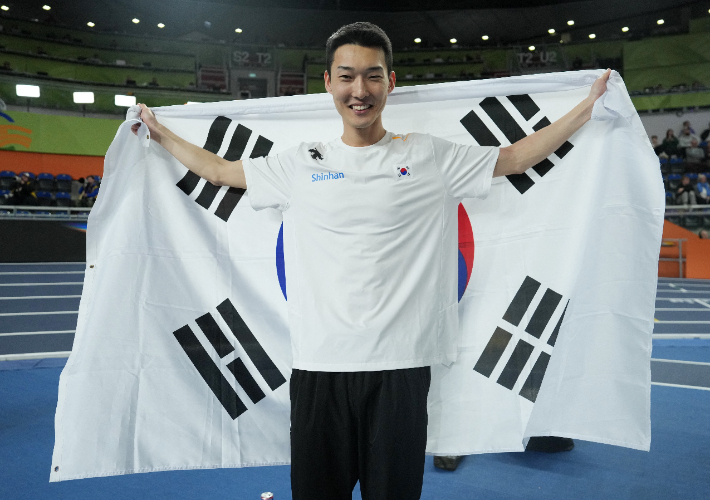우상혁이 2026 세계실내육상경기선수권대회 남자 높이뛰기에서 3위에 오른 뒤 태극기를 들고 포즈를 취하고 있다. 연합뉴스