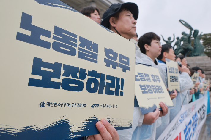 18일 국회 본청 앞 계단에서 전국공무원노동조합과 대한민국공무원노동조합총연맹이 연 공무원 노동절 휴무 쟁취 기자회견에서 참석자들이 손팻말을 들고 있다. 연합뉴스