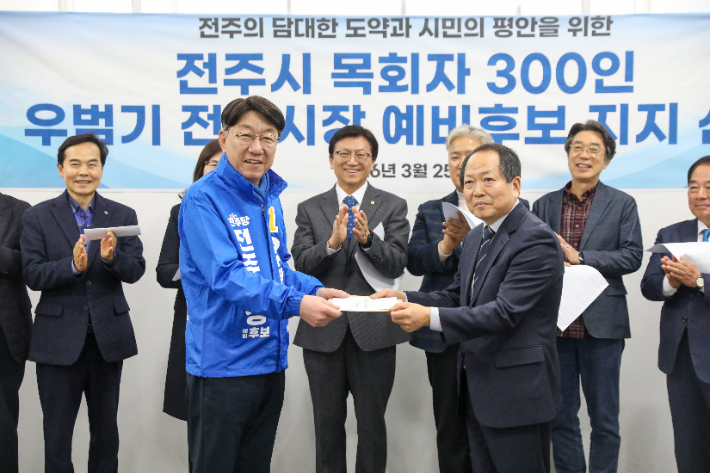 사랑하는교회 이상규 목사가 전주시 목회자 300여 명의 이름이 담긴 지지 선언 명단을 우범기 전주시장 예비후보에게 전달하고 있다. 최화랑 기자