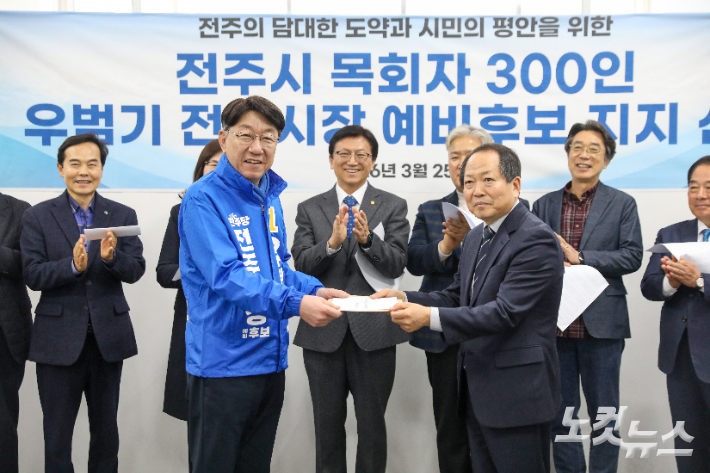 사랑하는교회 이상규 목사가 전주시 목회자 300여 명의 이름이 담긴 지지 선언 명단을 우범기 전주시장 예비후보에게 전달하고 있다. 최화랑 기자