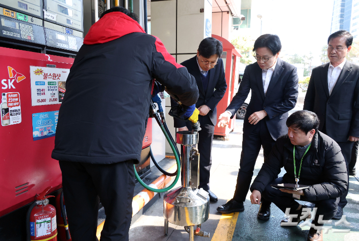 김정관 산업통상부 장관이 석유 최고가격제 시행 첫날이었던 13일 서울 마포구 한 주유소를 찾아 정량기준탱크를 보며 한국석유관리원 관계자의 설명을 듣고 있다. 황진환 기자