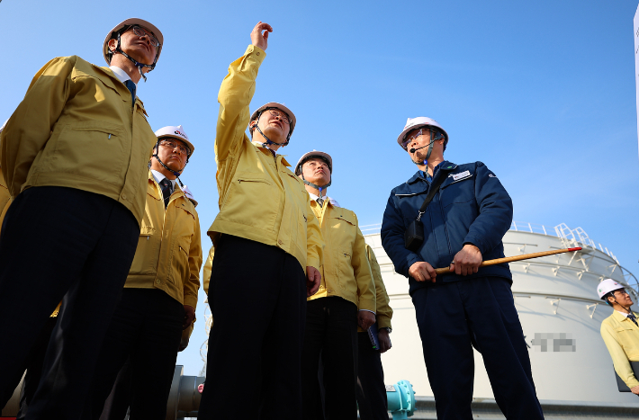 이재명 대통령이 지난 26일 충남 한국석유공사 서산 비축기지에서 석유화학기업 간담회를 마친 뒤 원유탱크를 살펴보며 관계자에게 질문하고 있다. 연합뉴스