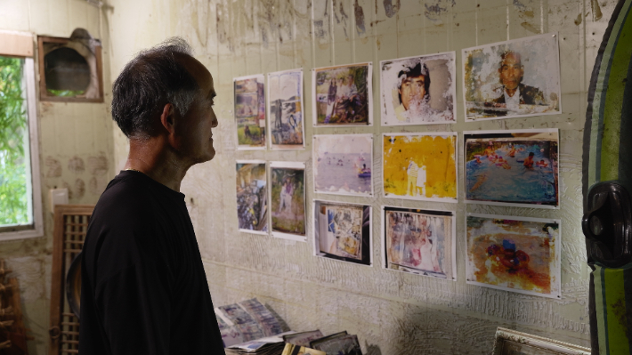 정뱅이 마을 수해 1주기 치유 행사에서 한 주민이 전시된 '물에 젖은 옛 사진'을 가만히 바라보고 있다. 예술가들과 주민들이 함께 트라우마를 극복하고 일상의 기억을 복원해 나가는 뭉클한 회복의 과정이 영화를 통해 묵직한 감동을 전한다. 하이든든 제공