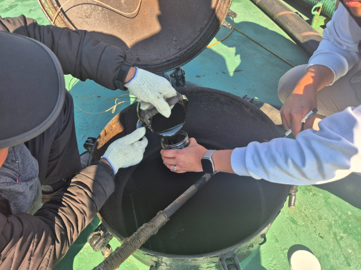 부산해경이 무자료 기름 공급선에서 시료를 채취하고 있다. 부산해양경찰서 제공