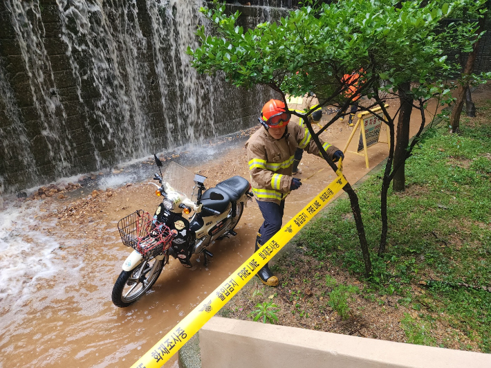 장마철 부산의 한 주택가 뒤편에서 토사 유출에 따른 안전조치가 이뤄지고 있다.  부산소방제난본부 제공
