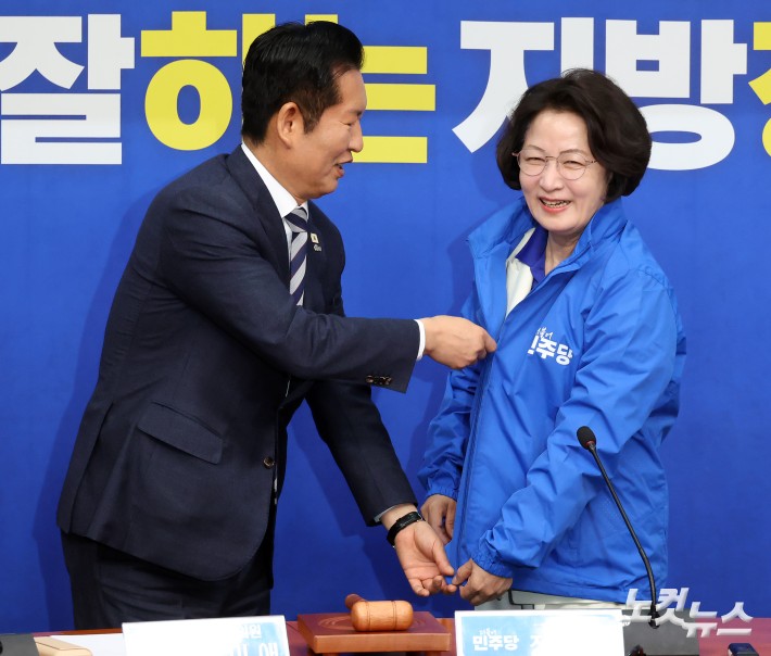 더불어민주당 정청래 대표가 13일 서울 여의도 국회에서 열린 경기도지사 후보 환영식에서 추미애 후보에게 당 점퍼를 입혀주고 있다.