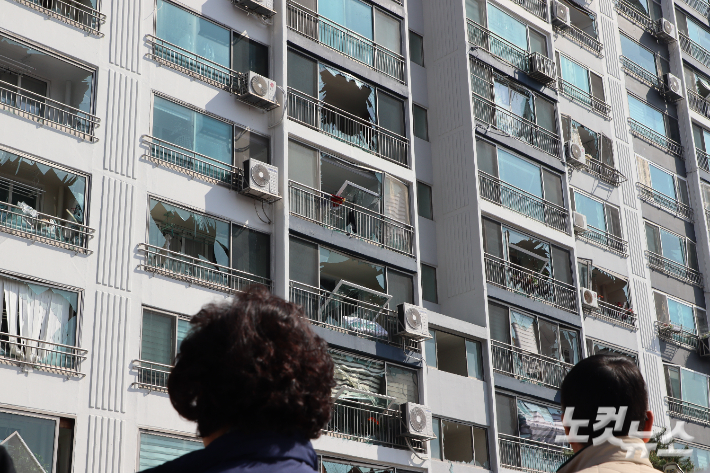 아파트 주민들이 폭발 사고로 피해를 입은 아파트를 바라보고 있다.