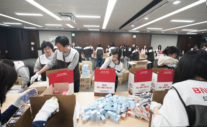 BNK경남은행 직원들이 본점 누리마당에서 'BNK 재난·재해 구호 KIT'를 제작하는 봉사활동에 참여하고 있다. BNK경남은행 제공 