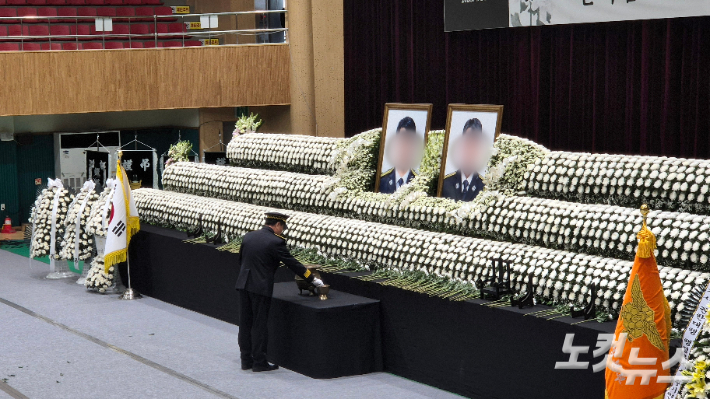 14일 오전 두 순직 소방관의 영결식이 거행된 전남 완도군 농어민문화체육센터. 영결식이 끝난 후 동료 소방관이 두 순직 소방관의 영정사진 앞에서 향에 불을 붙이고 있다. 한아름 기자