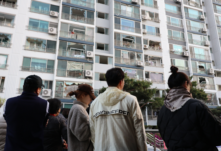 13일 오전 청주시 흥덕구 봉명동의 한 아파트 주민들이 폭발 사고 여파로 깨진 창문을 바라보고 있다. 연합뉴스