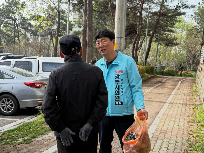 전남광주특별시의원 후보인 진보당 소재섭 후보가 북구의 한 공원에서 쓰레기를 줍고 주민과 대화하고 있다. 소 후보 측 제공