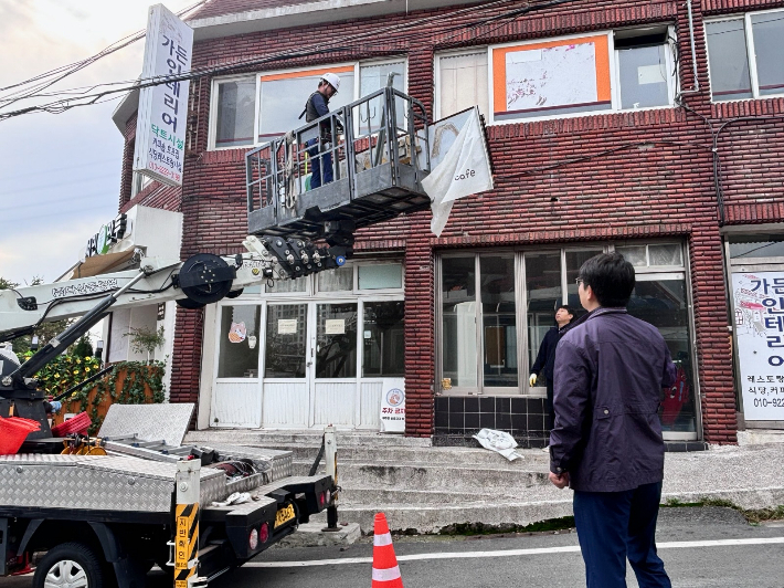 빈 점포의 주인 없는 노후간판을 제거하고 있다. 자료사진