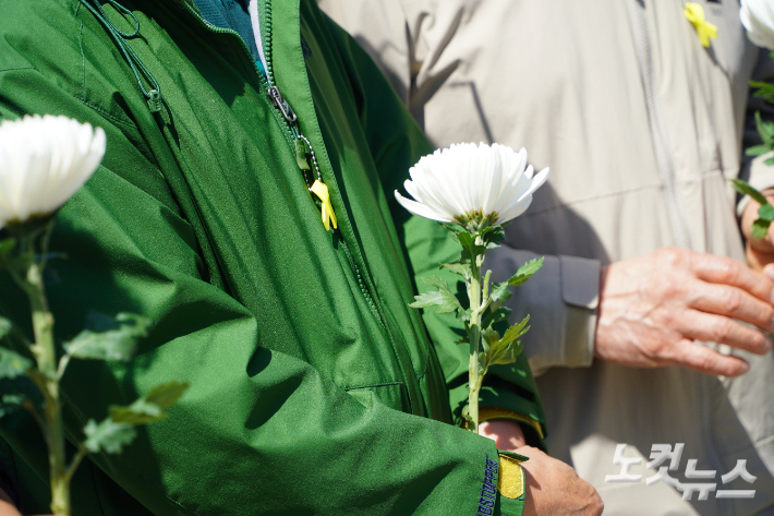 12주기를 맞은 세월호 참사를 추모하기 위한 시민의 손에 국화꽃이 들려있다. 상의 지퍼엔 노란 리본이 달려있다. 심동훈 기자