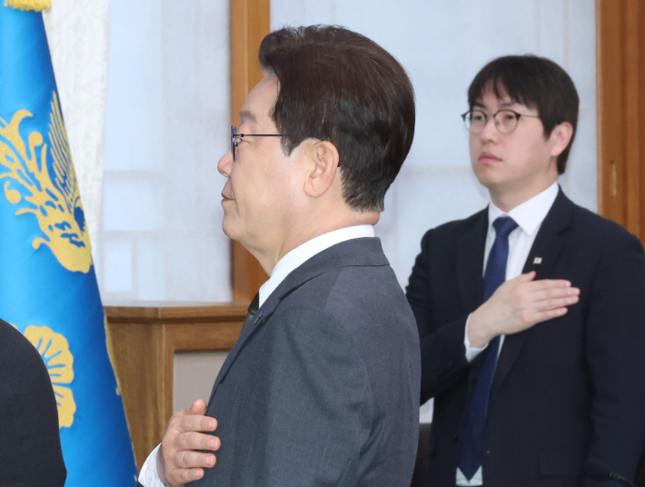이재명 대통령이 14일 청와대에서 열린 국무회의 겸 비상경제점검회의에서 국기에 경례하고 있다. 오른쪽은 하정우 AI미래기획수석. 연합뉴스